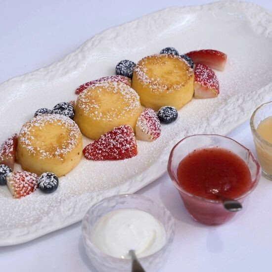 Syrniki with condensed milk, jam, and sour cream