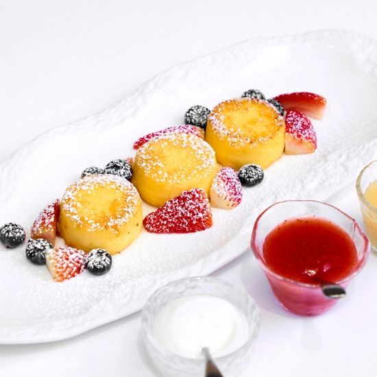 Syrniki with condensed milk, jam, and sour cream