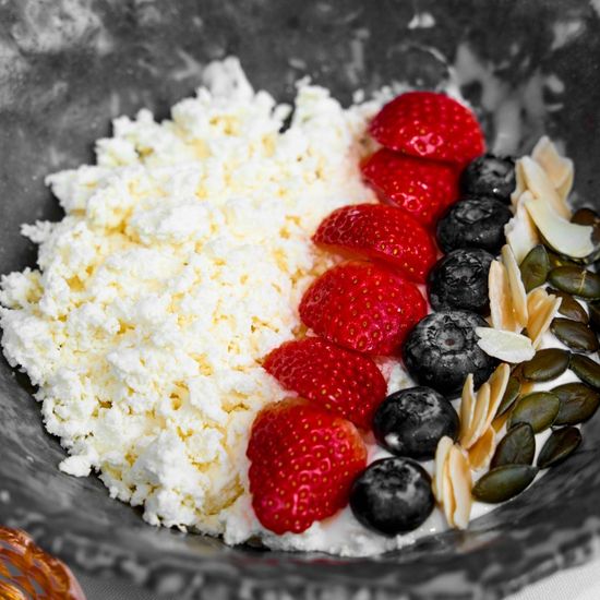 Cottage cheese bowl with fresh berries, served with honey
