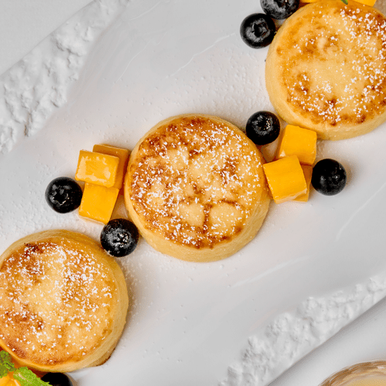 Syrniki with condensed milk, jam, and sour cream